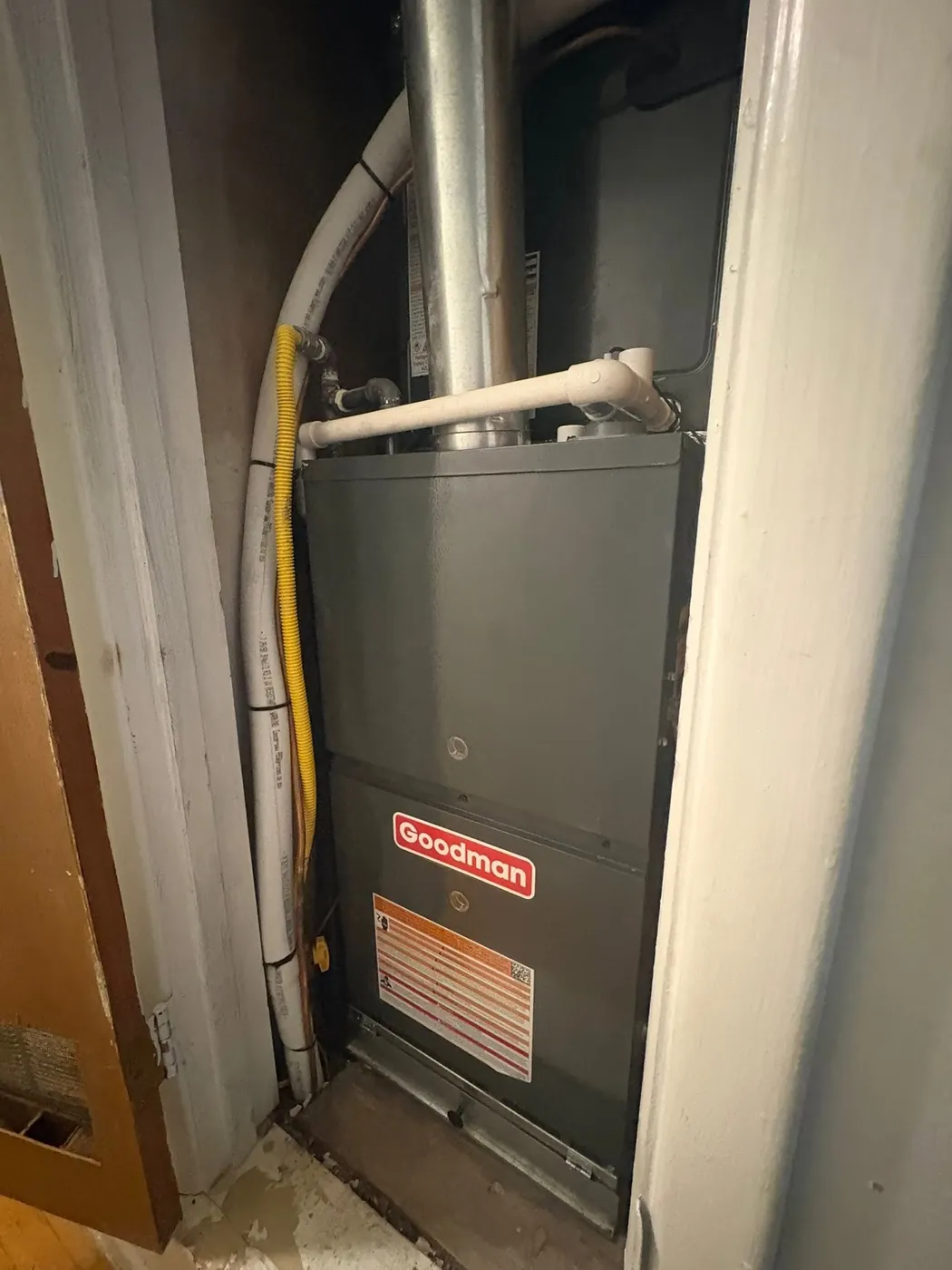 Goodman gas furnace in a closet with a yellow gas line and vent pipe