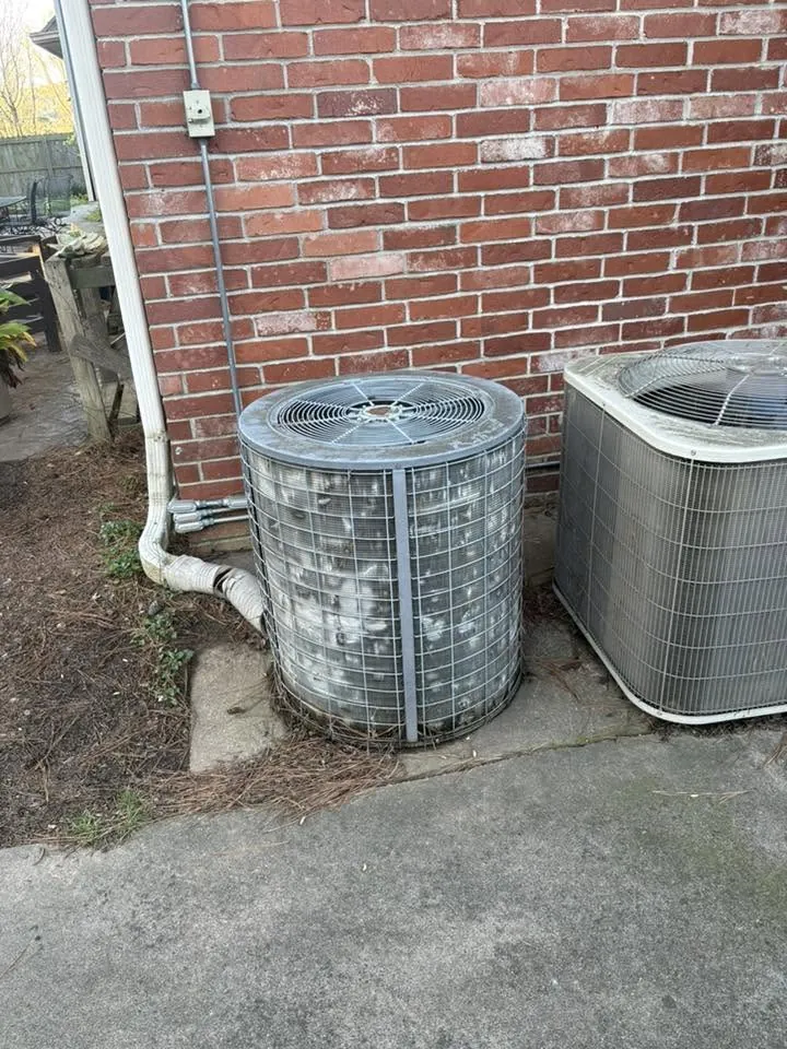 Two outdoor condensers beside a red brick wall